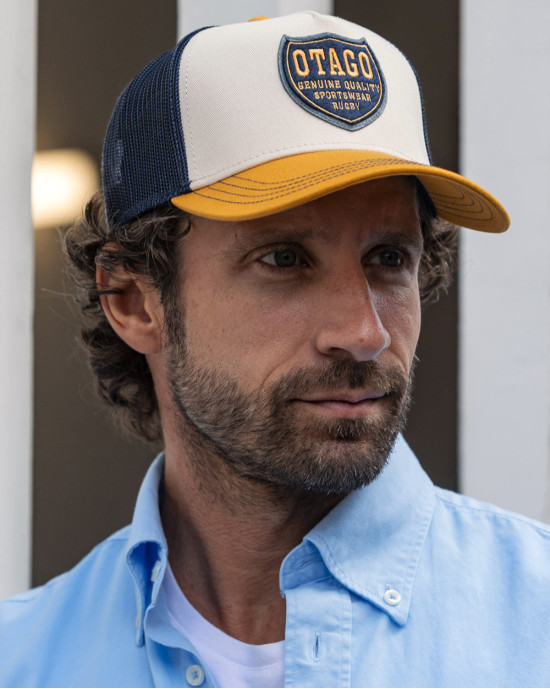 le modèle porte une Casquette Qualicap Otago rugby écru ocre et marine